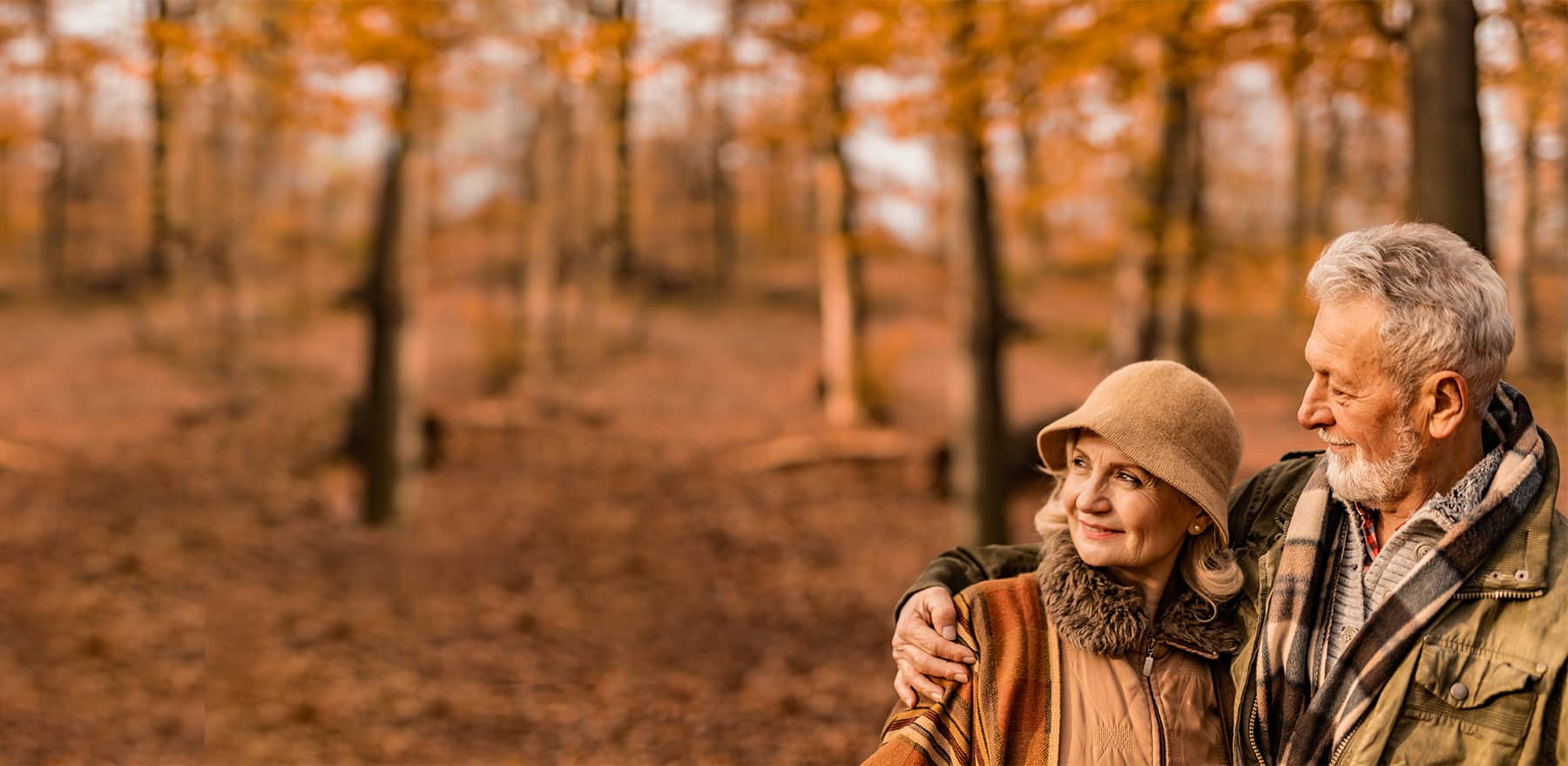 Close up senior woman hugging husband from behind at forest